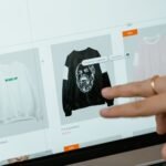 Close-up of hands interacting with a shopping website on a laptop screen indoors.